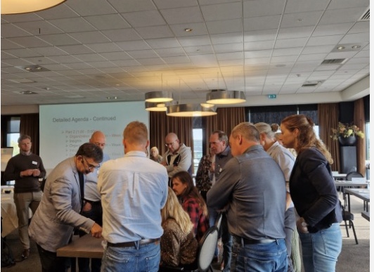 Deelnemers werken in een kleine groep rond een tafel tijdens een praktijksessie